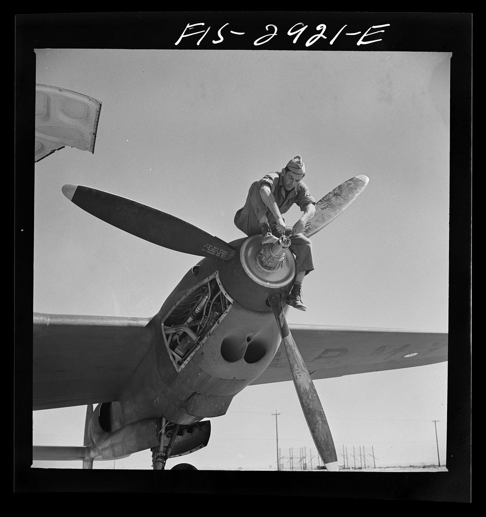 Working on the propeller hub of an interceptor plane. Lake Muroc, California by Russell Lee