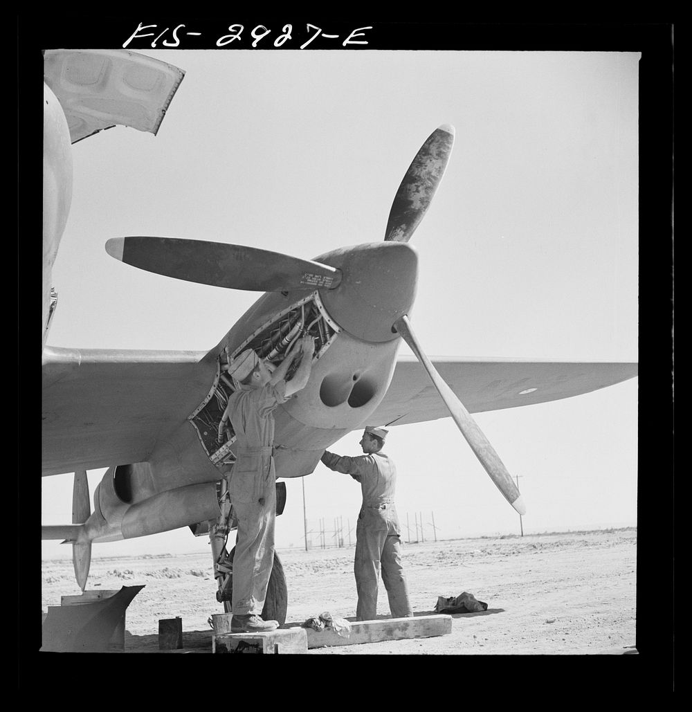 [Untitled photo, possibly related to: Working in the motor of an interceptor plane. Lake Muroc, California] by Russell Lee