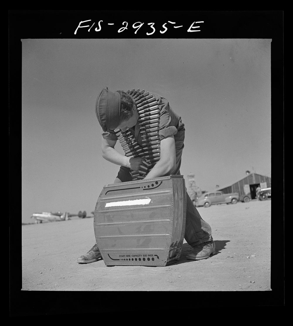 Lake Muroc, California. An armorer placing fifty caliber machine gun bullets in a magazine by Russell Lee