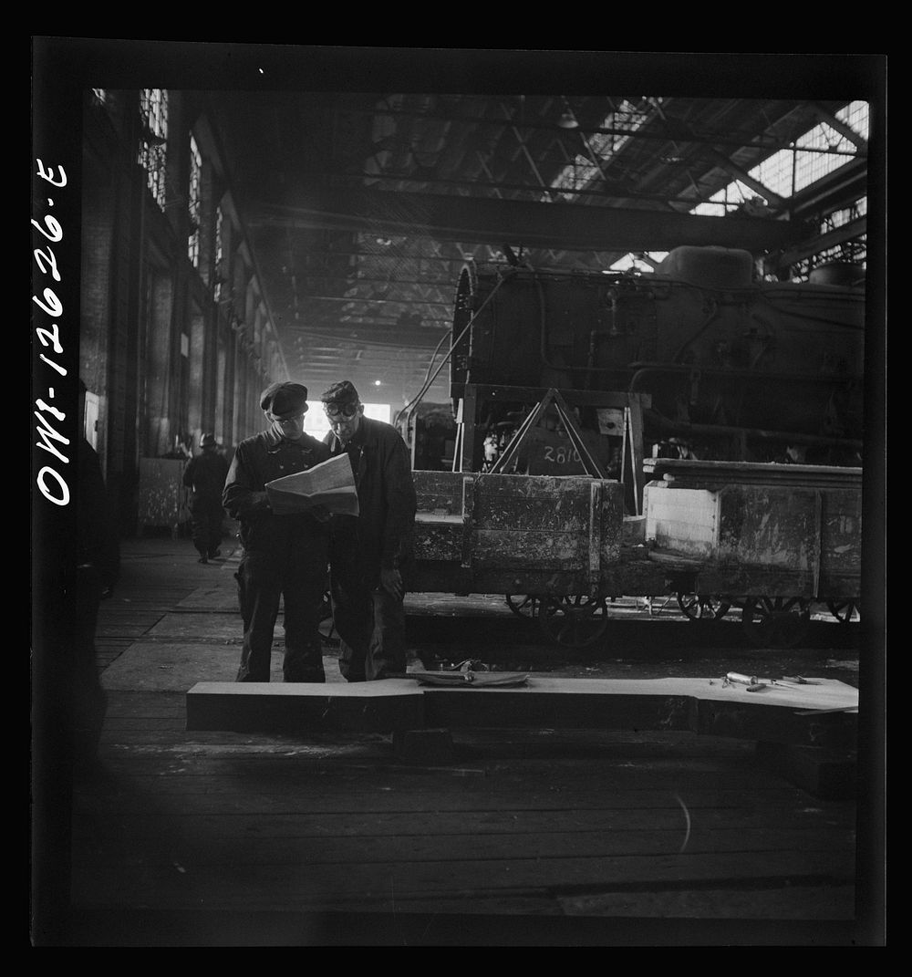 Chicago, Illinois. Workmen studying blueprints in the locomotive shops of the Chicago and Northwestern Railroad. The long…