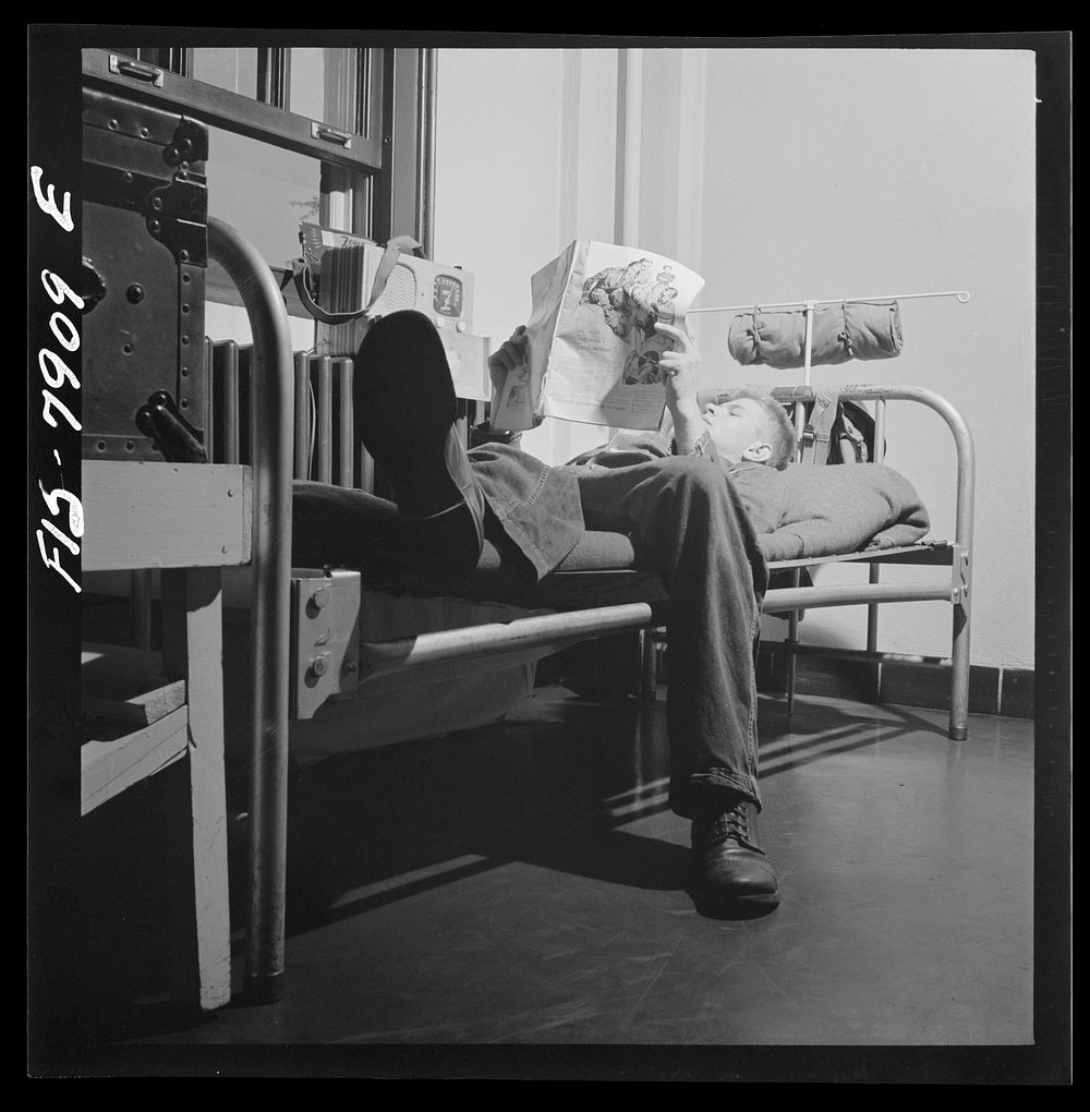 Fort Belvoir, Virginia. Sergeant George Camblair reading an article in a magazine while relaxing after dinner. Sourced from…