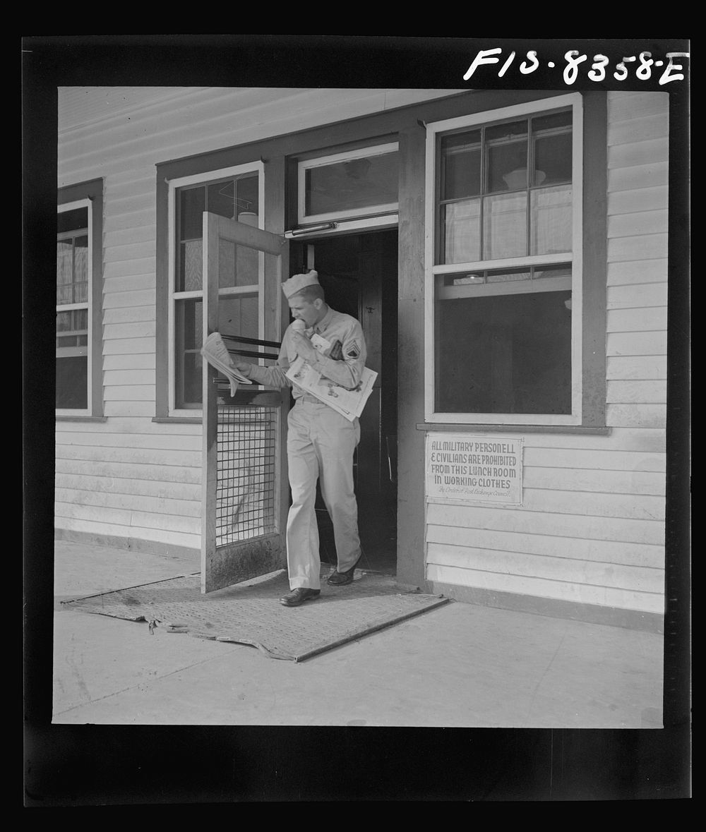 Fort Belvoir, Virginia. Sergeant George Camblair coming out of the post exchange with newspapers and ice cream. Sourced from…