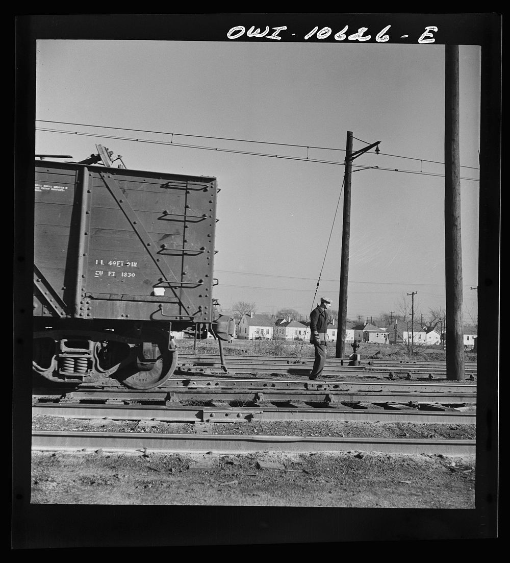 Chicago, Illinois. Brakeman going on the late afternoon shift, waiting to hop an engine to take him to his place of work in…
