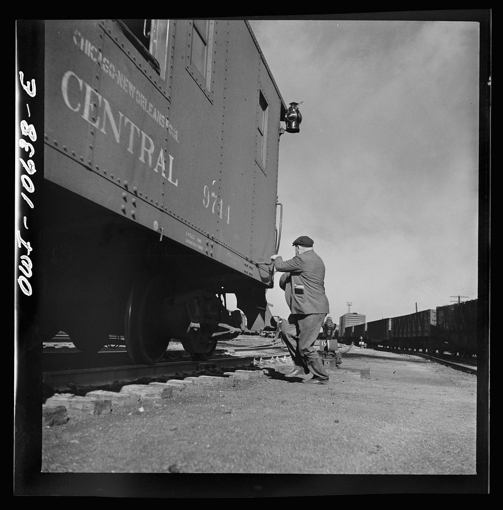 Chicago, Illinois. Conductor hopping aboard the caboose of a southbound freight at an Illinois Central Railroad yard.…