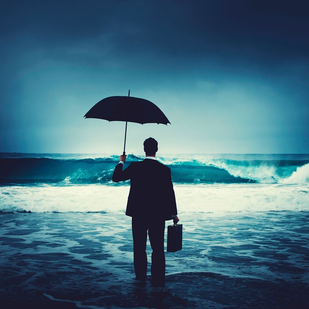 Businessman with an umbrella on the beach