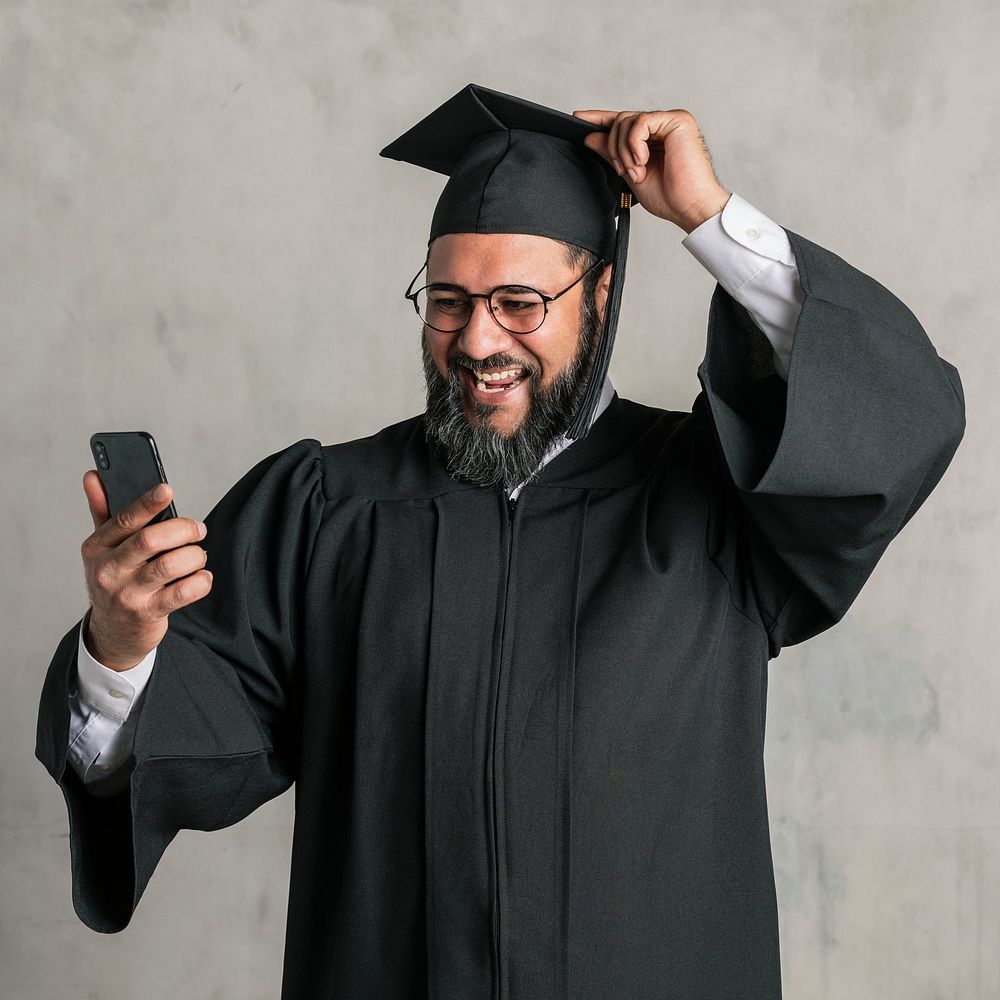 Senior man in a graduation gown using his mobile phone 