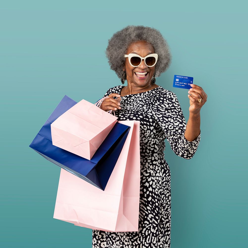 Cheerful black senior woman with shopping bags and a credit card mockup 