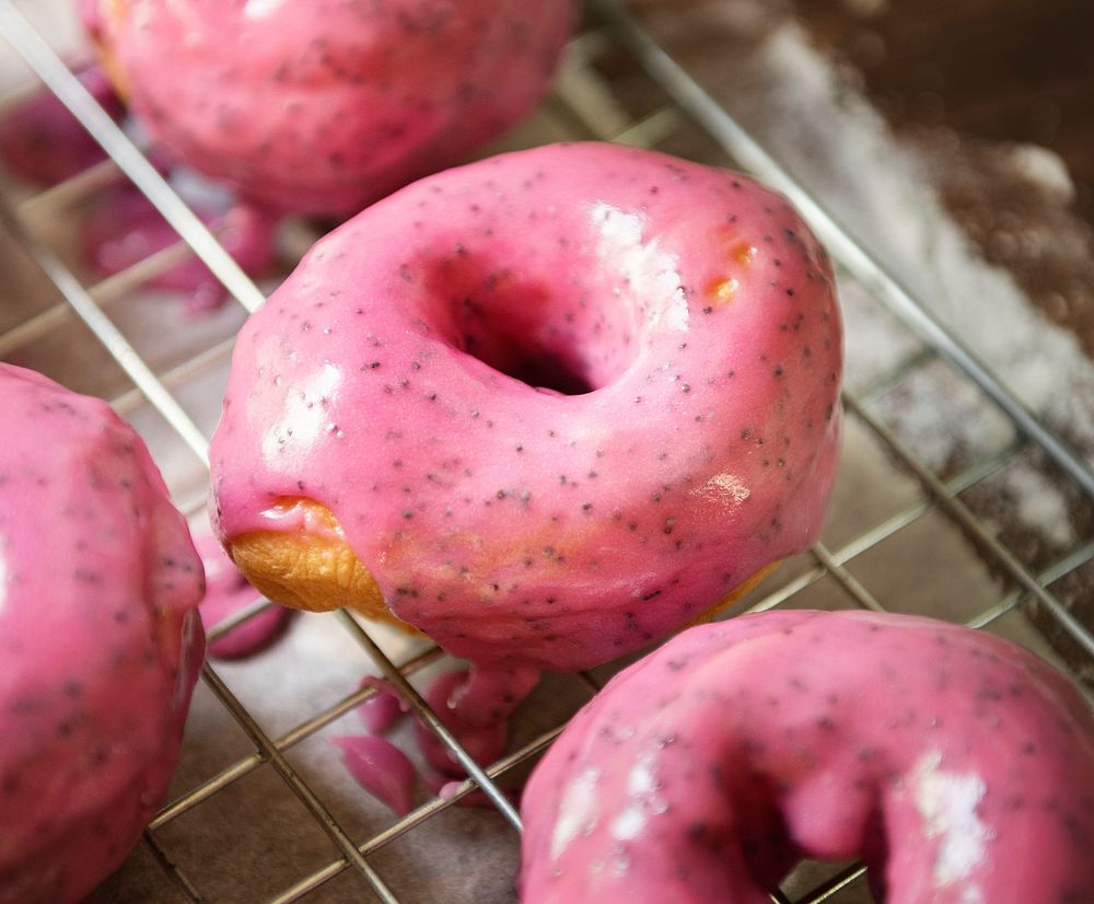 Pink glazed donuts on a cooling rack