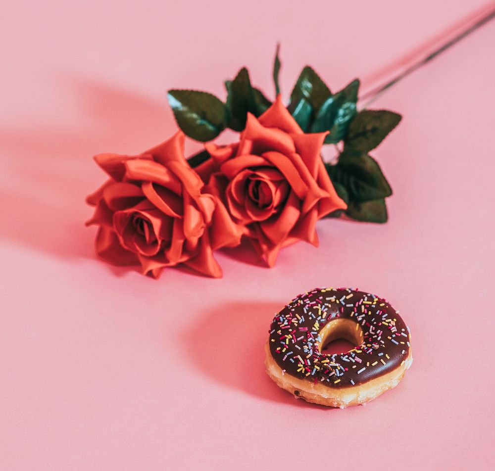 Tasty glazed donut beside a rose
