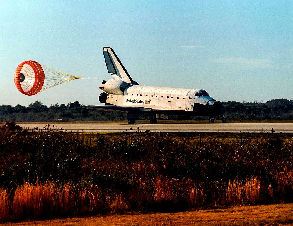 With its drag chute deployed, the Space Shuttle orbiter Atlantis touches down on Runway 33. Original from NASA. Digitally…
