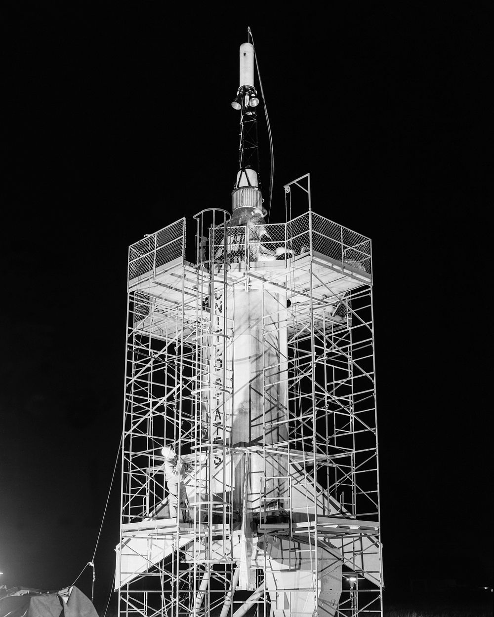 The Mercury capsule and escape tower are being lowered onto the Little Joe booster for launch on August 21, 1959. Original…