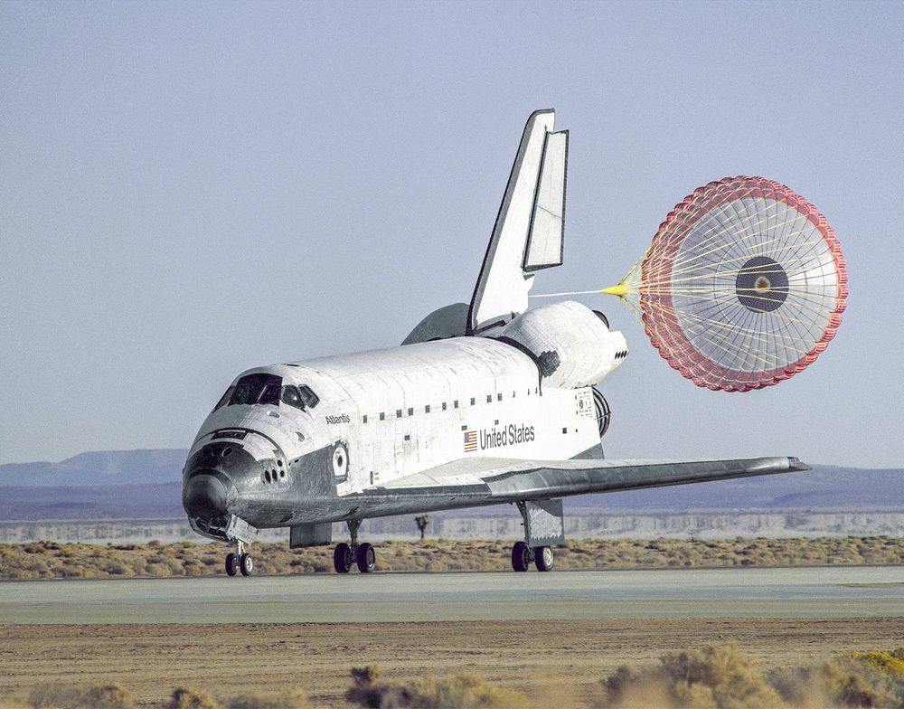 The space shuttle Atlantis lands with its drag chute deployed on runway 22 at Edwards, California. Original from NASA.…