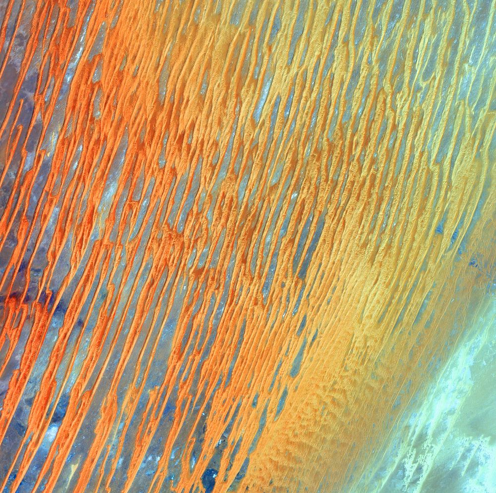 Ribbons of Saharan sand dunes seem to glow in sunset colors. Original from NASA. Digitally enhanced by rawpixel.
