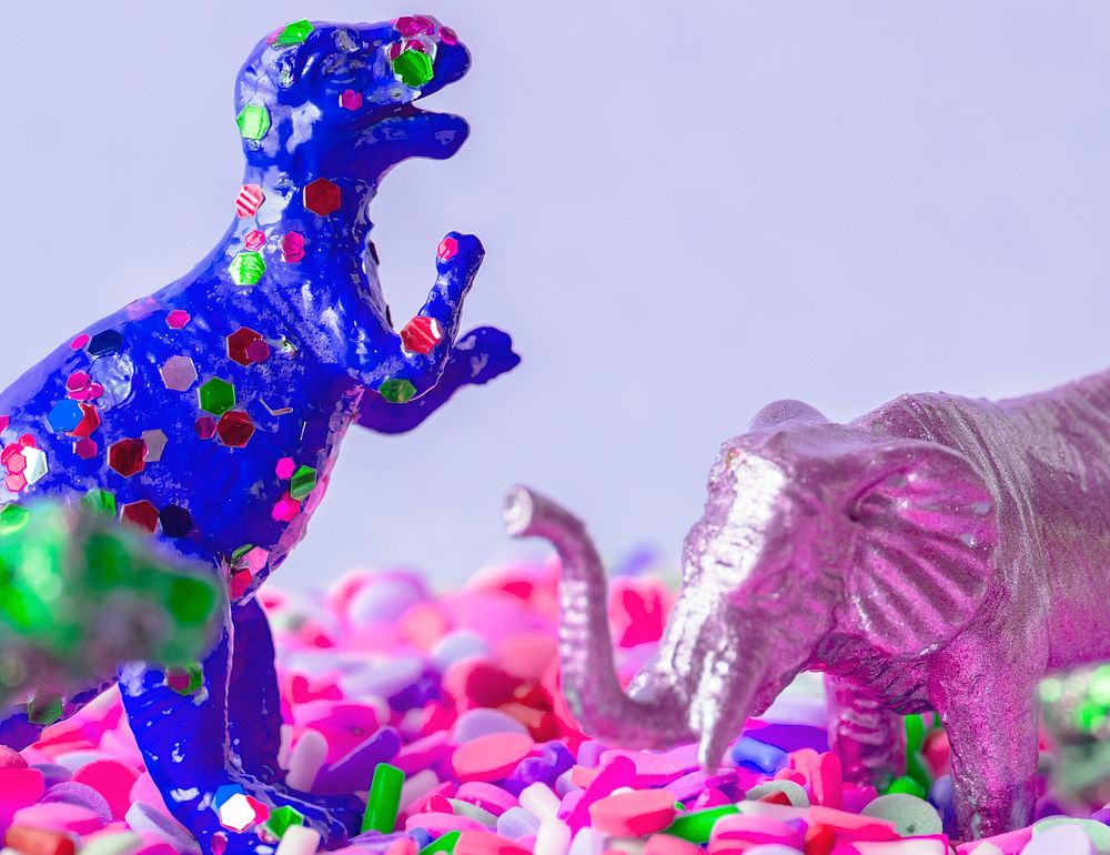 Close up of dinosaurs and animal figure toys on sweet candy sprinkles