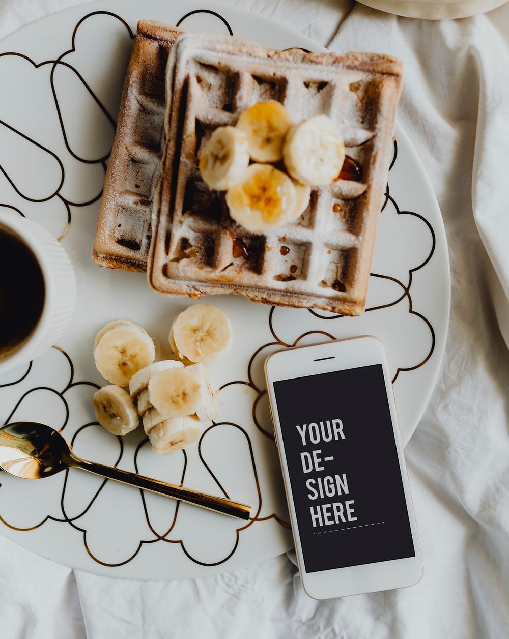 Plate of waffle with slices of banana and a cup of coffee next to a smartphone