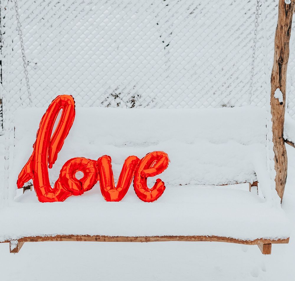 Red love balloon word on a snowy swing