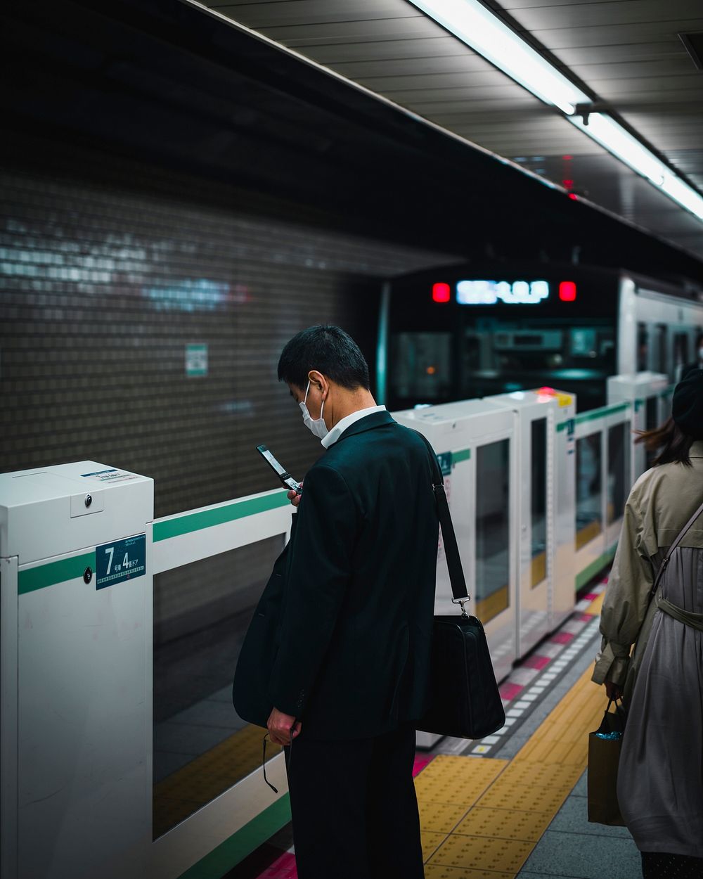 Japanese businessman waiting for a train at a platform
