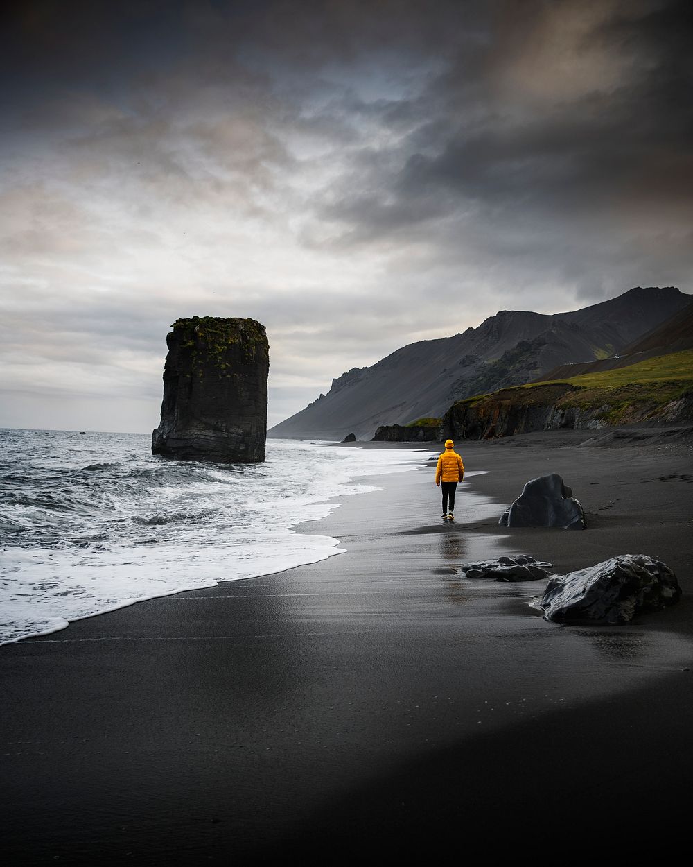 Man walking along a black beach in Iceland