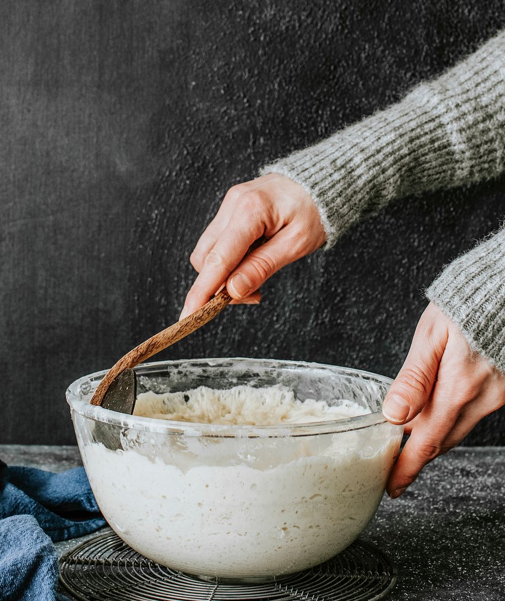 Baker kneading dough in a glass bowl
