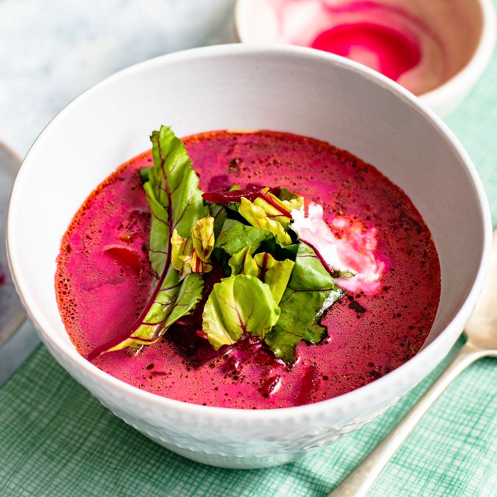A bowl of healthy beetroot leaf soup with cream on a table