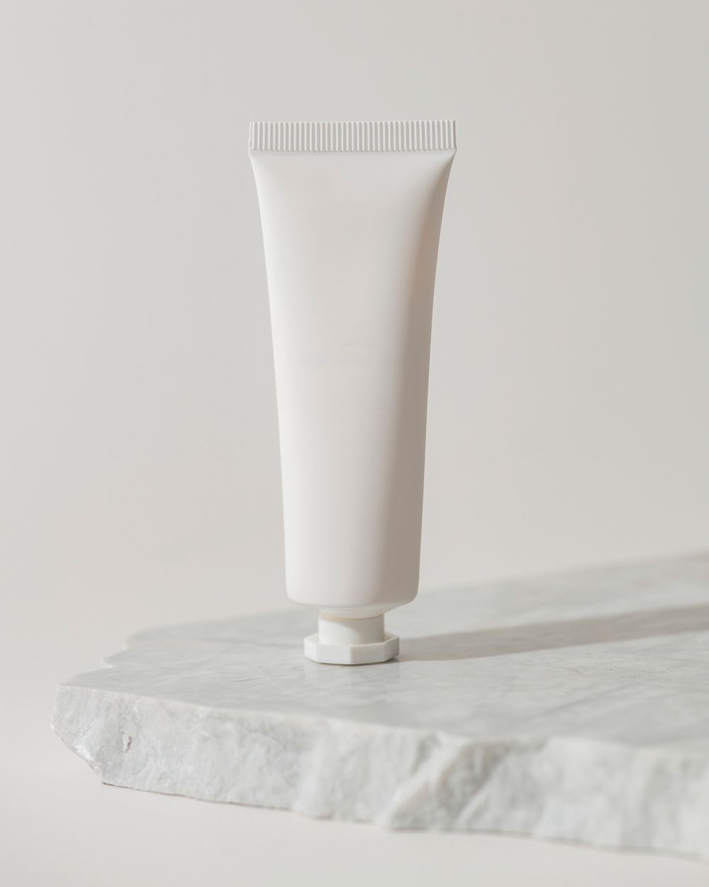 White tube, simple skincare product packaging, on marble product stand