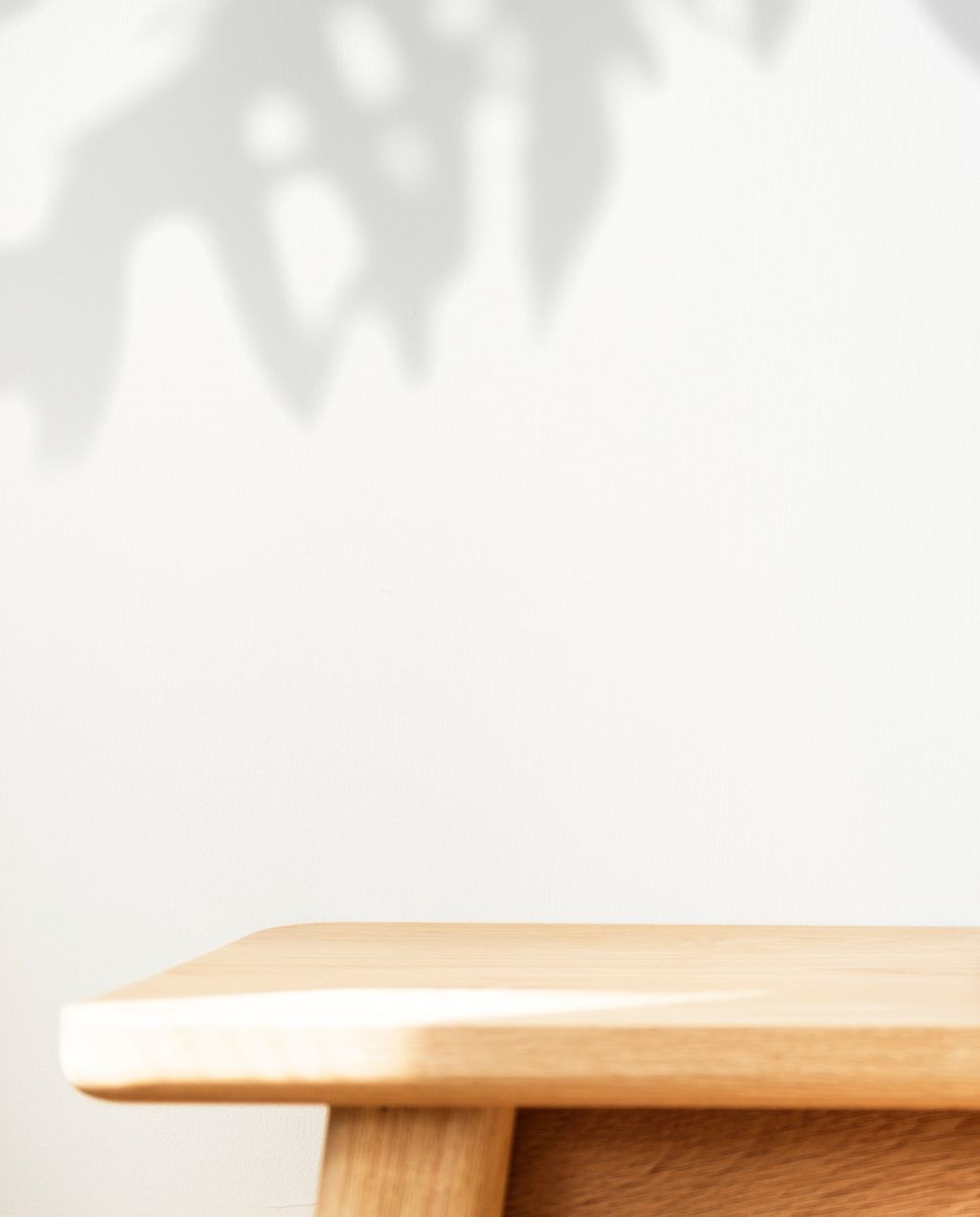 Wooden table with plant shadow on a wall