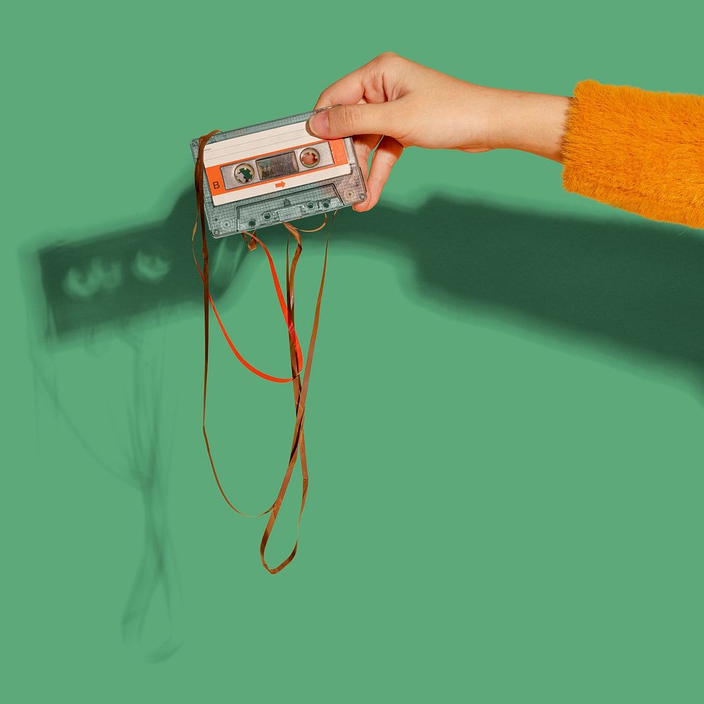 Woman holding an old school cassette tape mockup on a green background