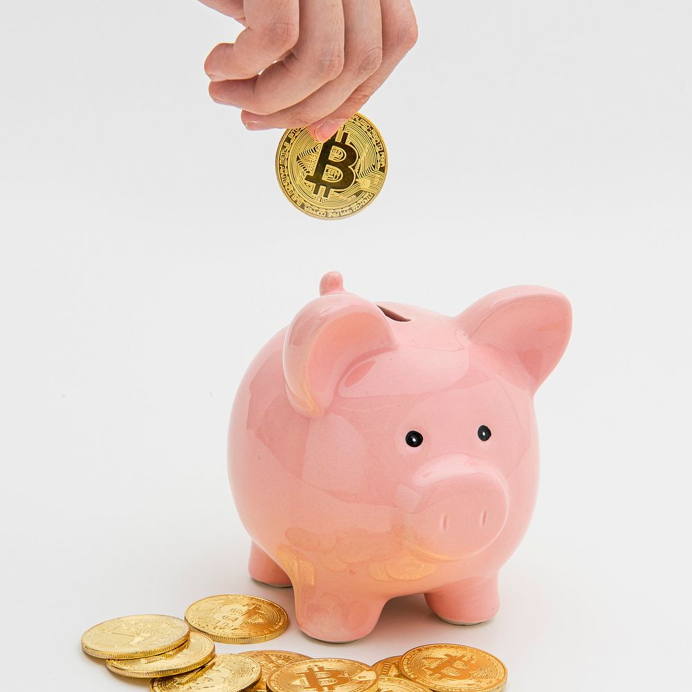 Woman inserting a bitcoin into a pink piggy bank