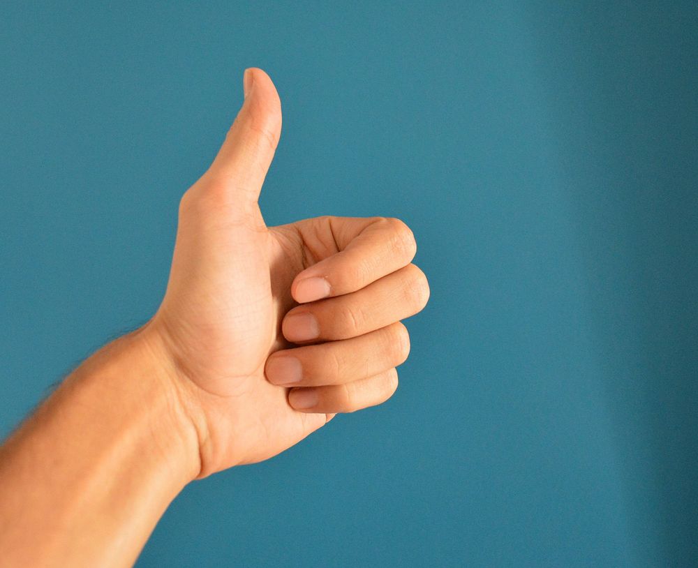 Free hand giving thumbs up on blue background image, public domain CC0 photo.