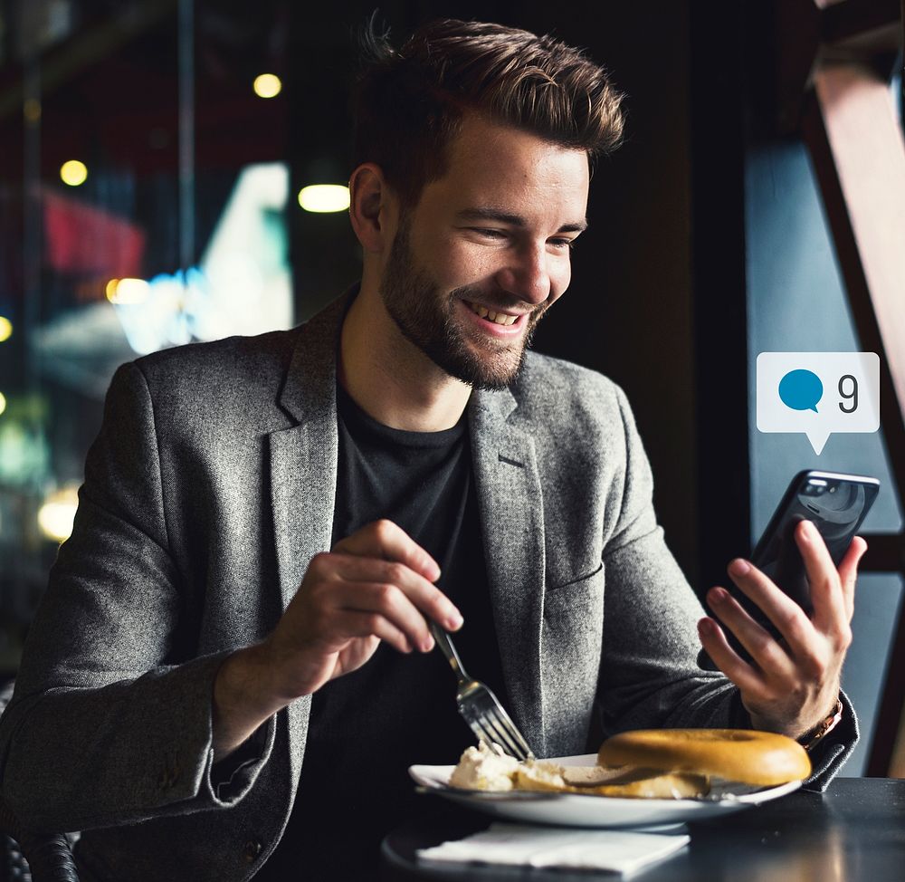 Happy man using social media on his smartphone in a cafe