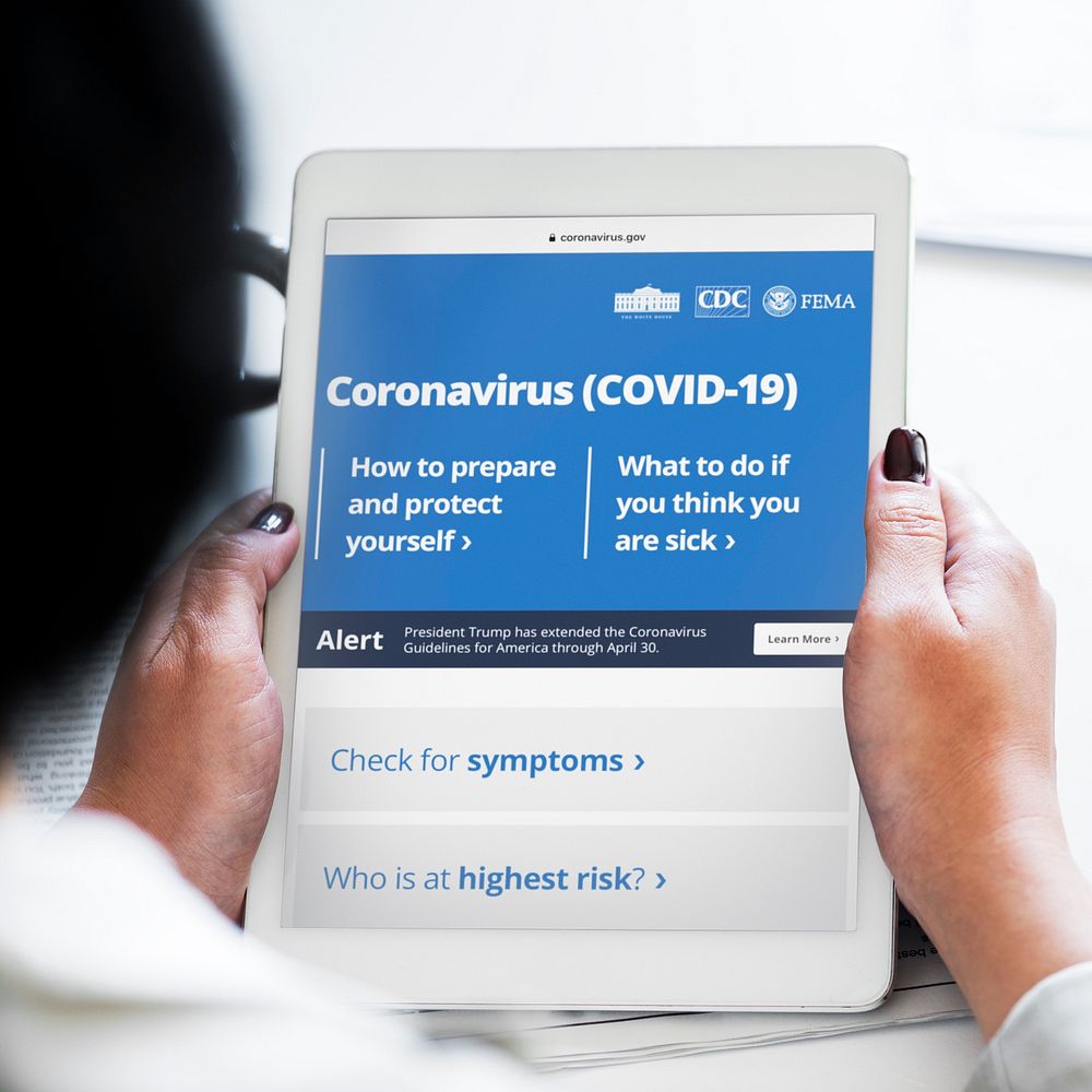 Woman reading coronavirus information from a tablet mockup with editorial graphic from https://www.coronavirus.gov/ accessed…