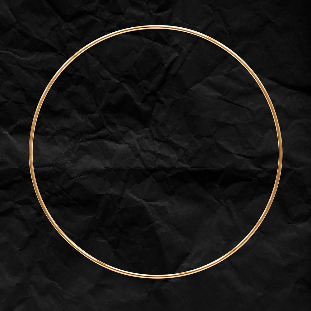 Round gold frame on a crumpled black paper textured background