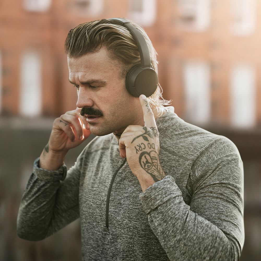 Handsome man wearing wireless headphones in the city remixed media