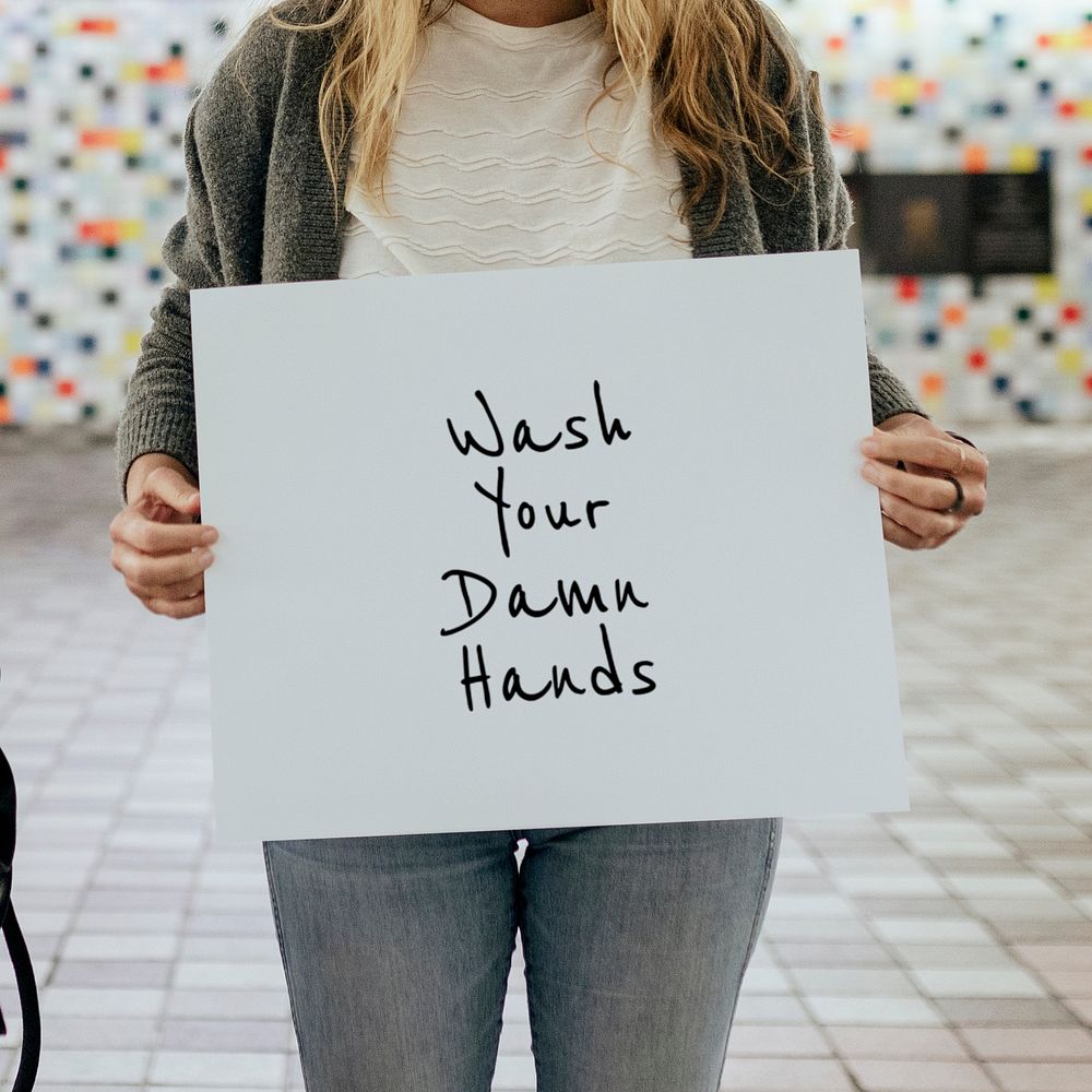 Woman holding wash your damn hands sign during the coronavirus outbreak 