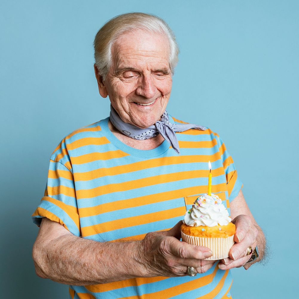 Senior man holding a birthday cupcake 