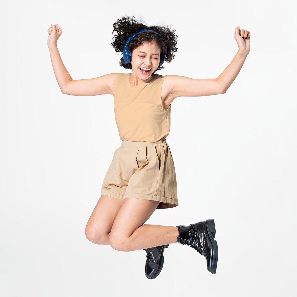 Happy woman jumping wearing headphones dancing to music
