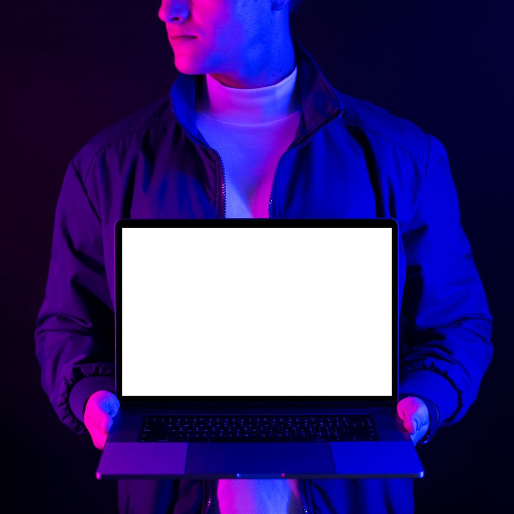 Businessman showing laptop blank screen in neon light
