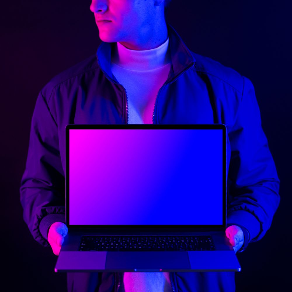 Businessman showing laptop in neon light