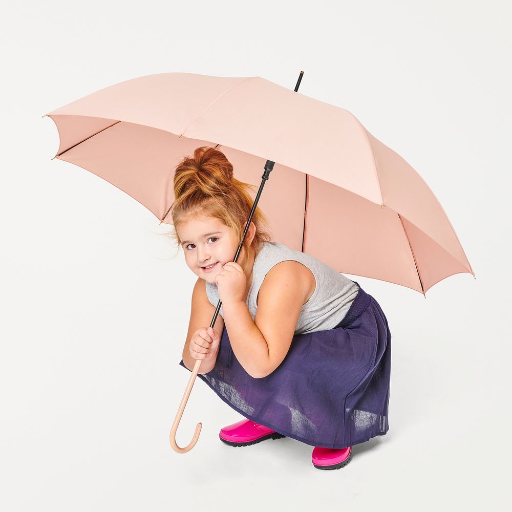 Little girl holding a pink umbrella in studio