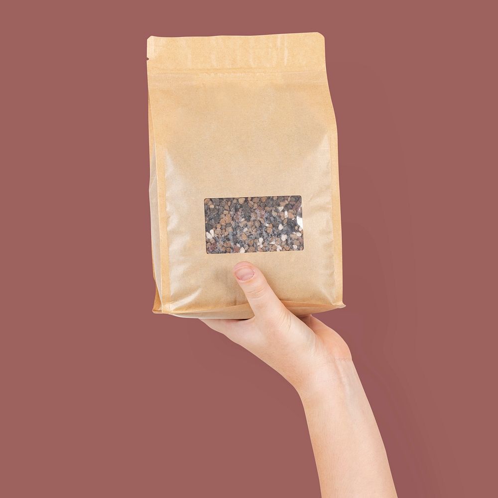 Hand mockup psd holding plant fertilizer in an eco-friendly packaging bag
