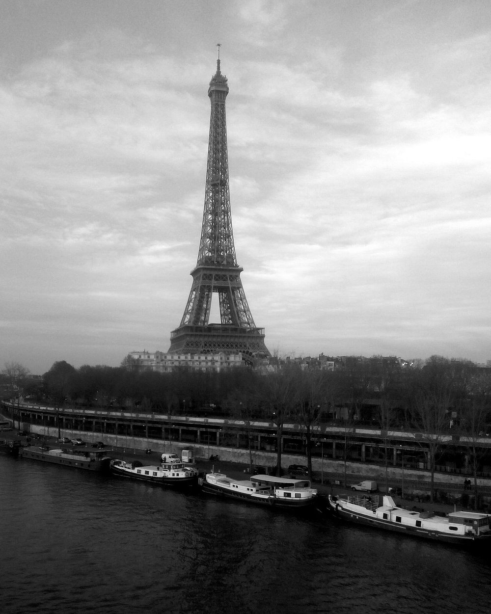 Black and white Eiffel Tower with boats along the river. Original public domain image from Wikimedia Commons