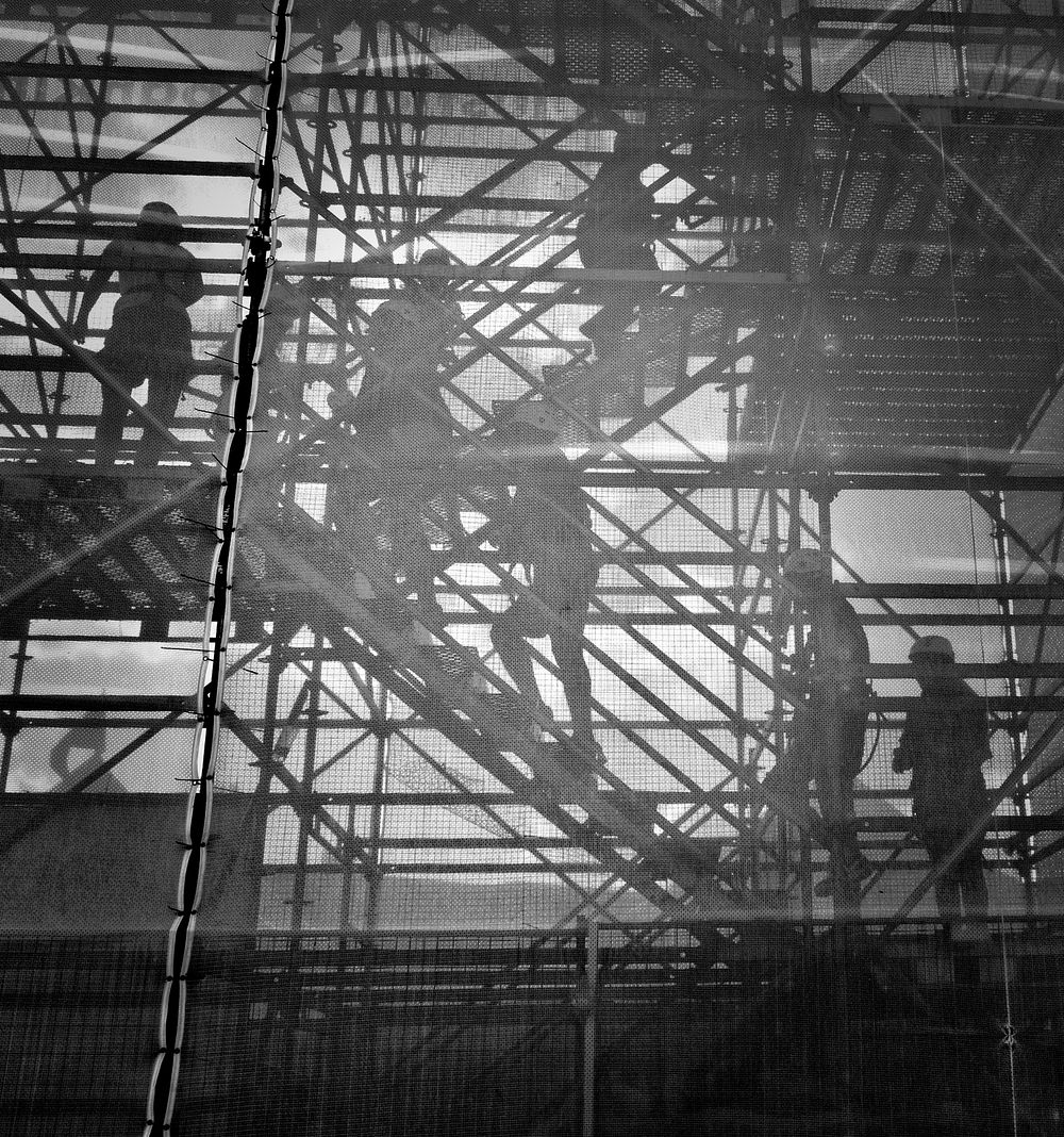 Construction workers walk up scaffolding to their site. Original public domain image from Wikimedia Commons