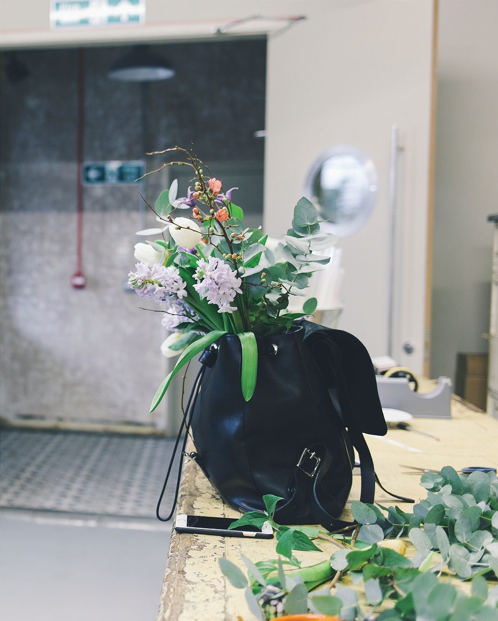 Florist's backpack full of flowers and leaves on workspace tabletop. Original public domain image from Wikimedia Commons