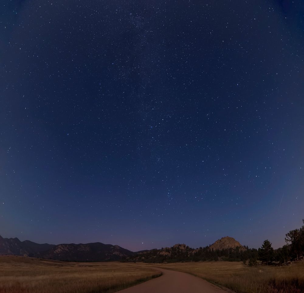 Winding country road under a blue starry night sky in Colorado. Original public domain image from Wikimedia Commons