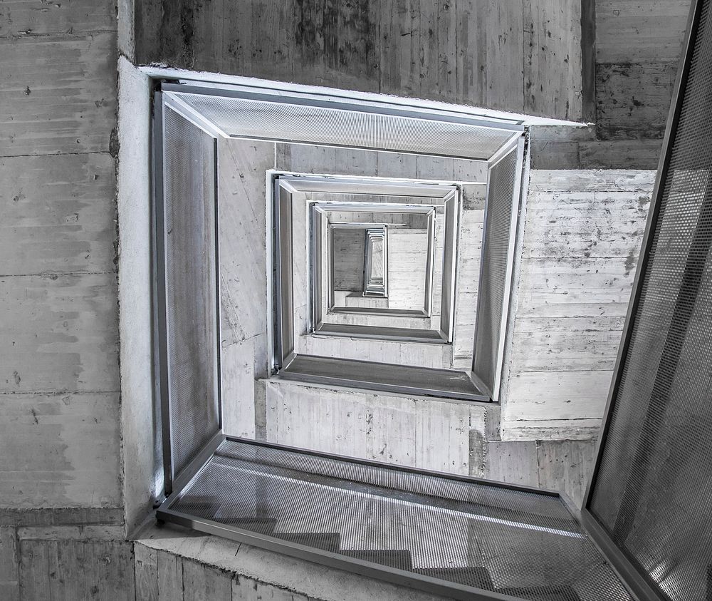 Looking down a gray rectangular stairwell inside. Original public domain image from Wikimedia Commons