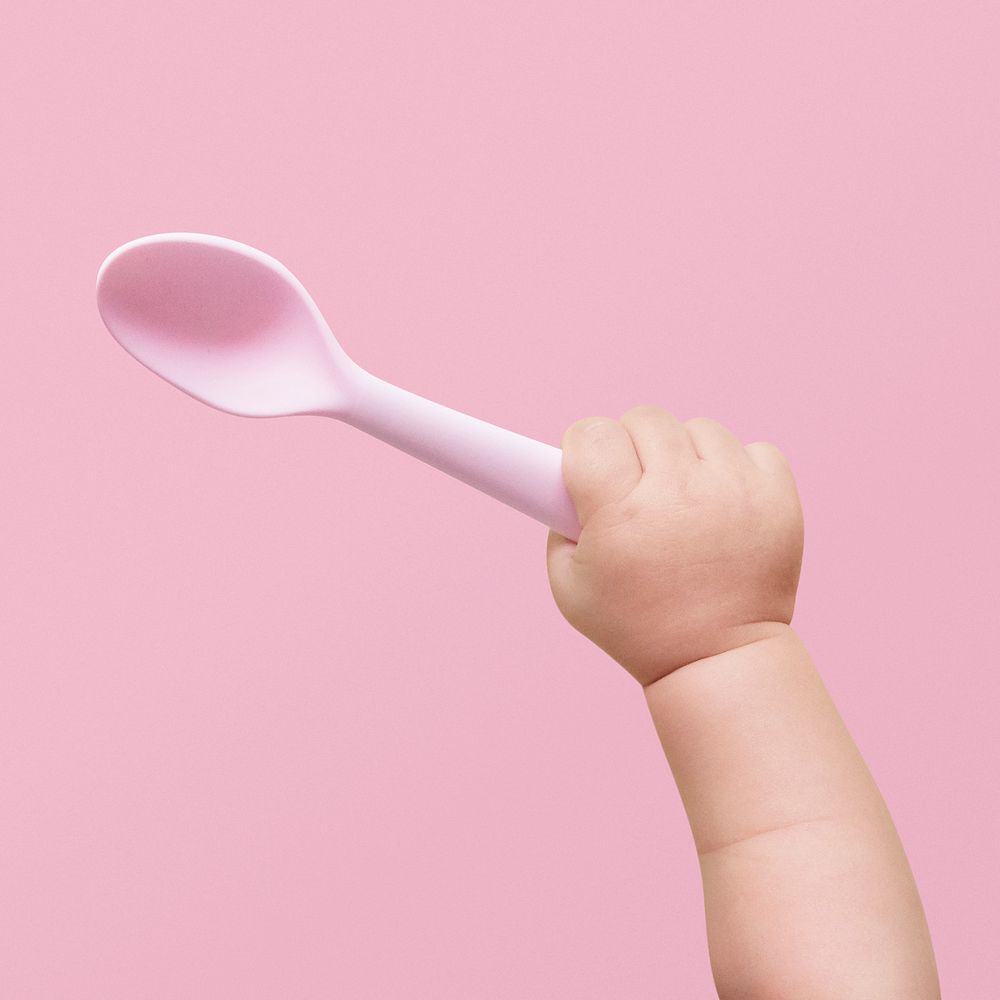 Baby hand holding spoon pink plastic image