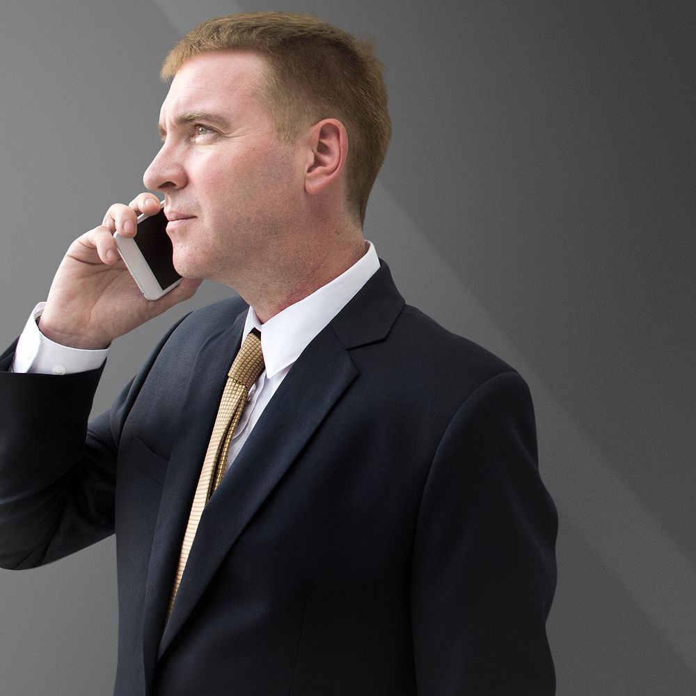 Businessman talking on phone on gray background