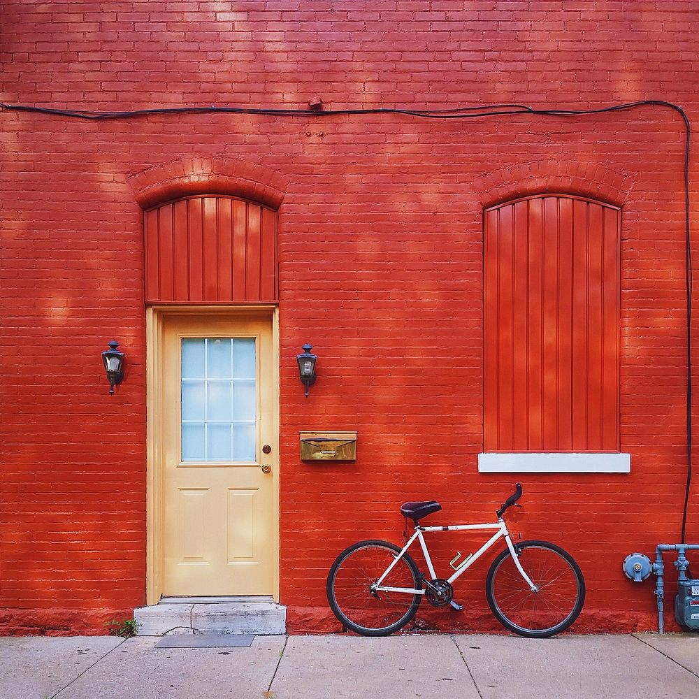 Red wall building with parked bicycle. Original public domain image from Wikimedia Commons